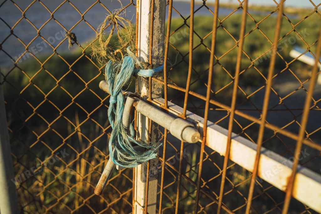 A closeup shot of a chain-link fence with a blue rope on it