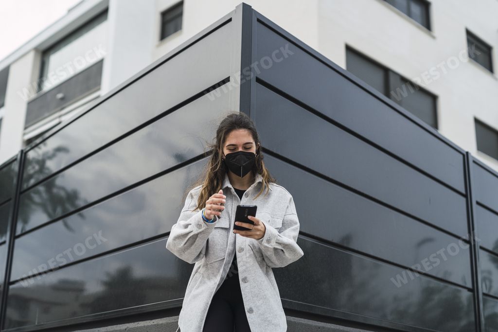 A young Spanish girl in a black face mask is making a video call while resting outside