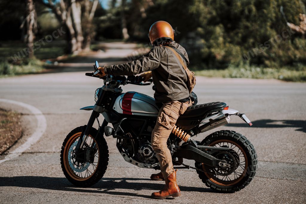 Man in helmet stands by motorcycle on urban street
