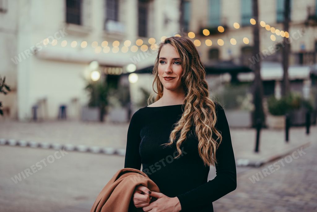 Woman walking down the street with coat draped over shoulder