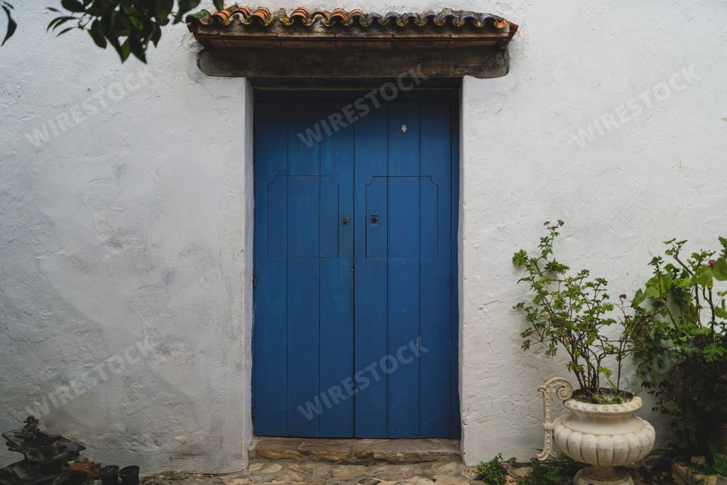 A beautiful view of a blue door in the white building of a small town in Spain