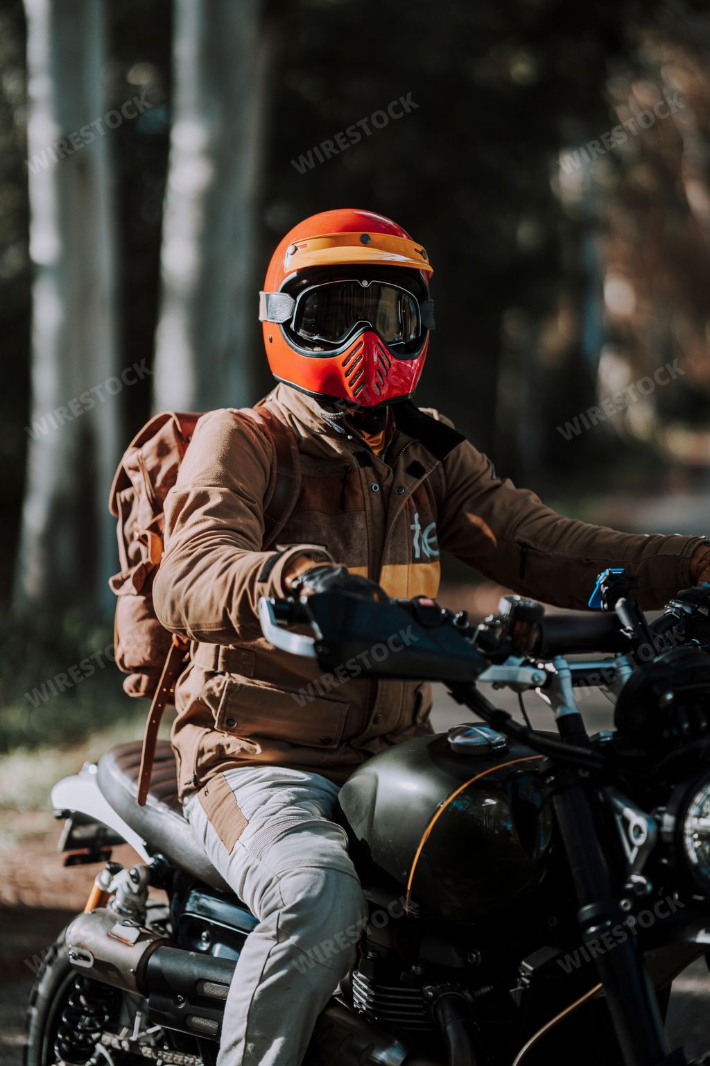 Man in red helmet rides motorcycle on dirt path