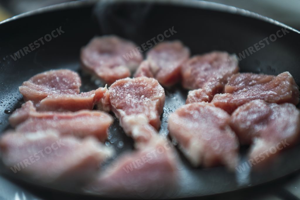 A macro shot of cuts of pork tenderloin cooking in a