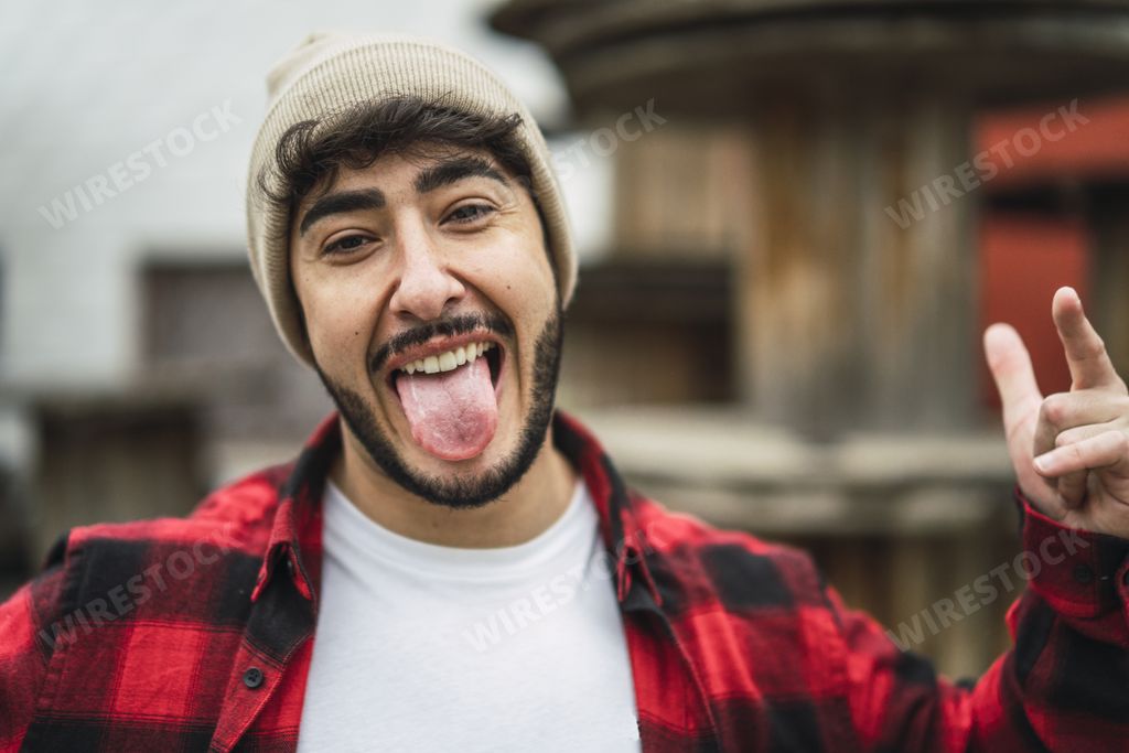 A portrait of a crazy Spanish guy wearing stylish clothes on background of industrial spools