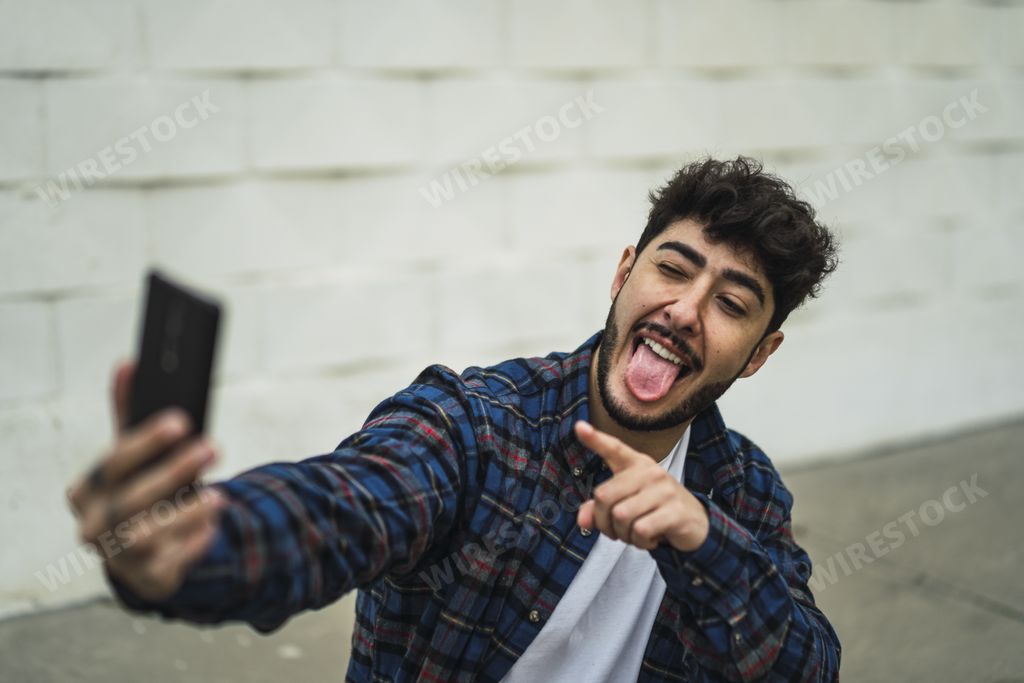 A cool Spanish male taking a selfie and pointing on the camera