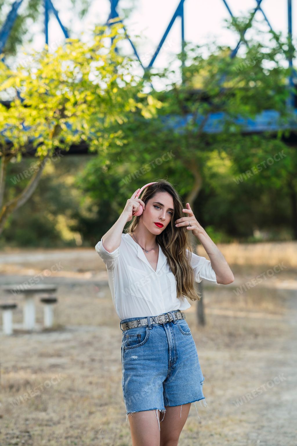 A stylish Spanish woman listening to music with wireless headphones in a park