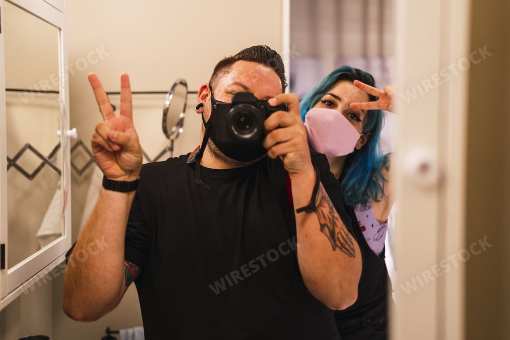 A male and female taking a selfie doing the 'peace sign' pose on a bathroom mirror