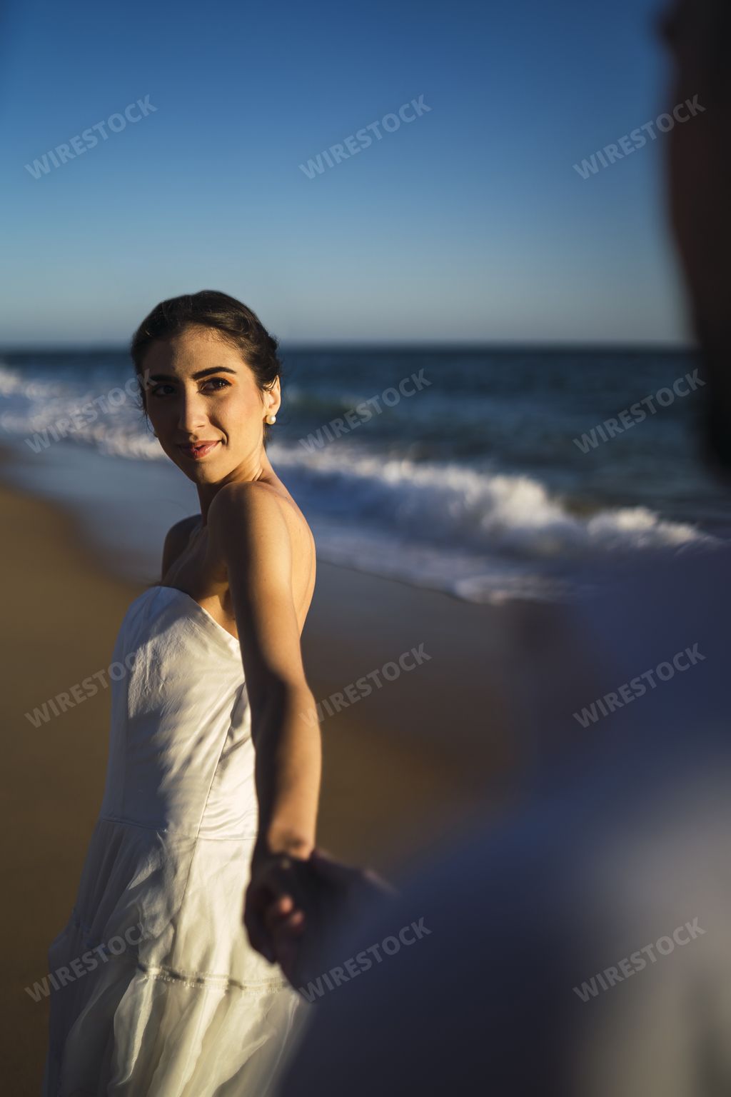 A vertical picture of a brunette female in a white dress with a sincere smile