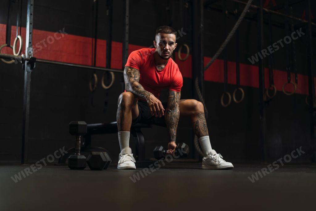 A strong muscular European guy with cool tattoos working out in a gym