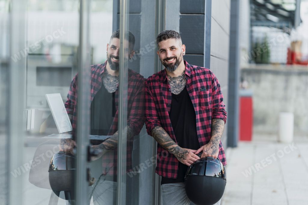 A handsome tattooed man posing while leaning on the window
