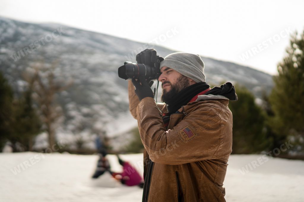A young bearded guy trying to capture something with his camera.