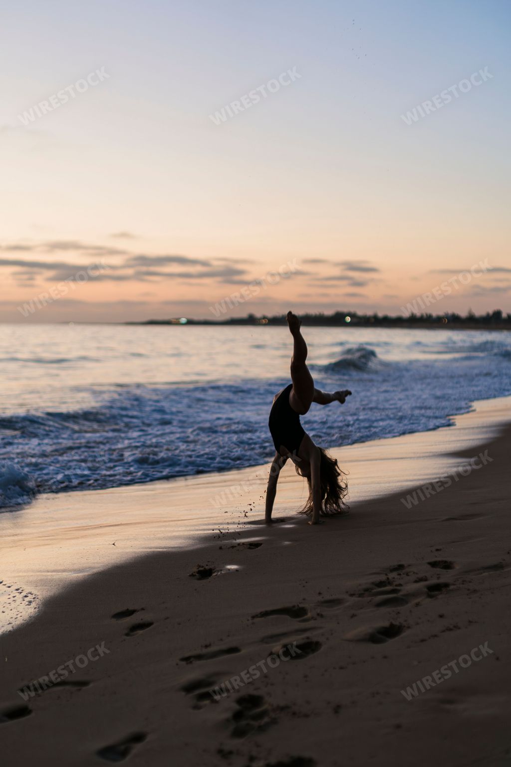 A person practicing yoga poses at sunset on a sandy beach.