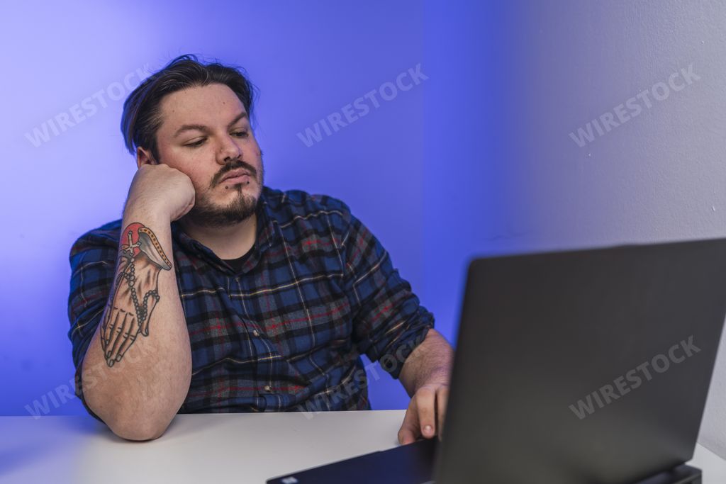 A man working on his laptop in an office room illuminated with blue led lights