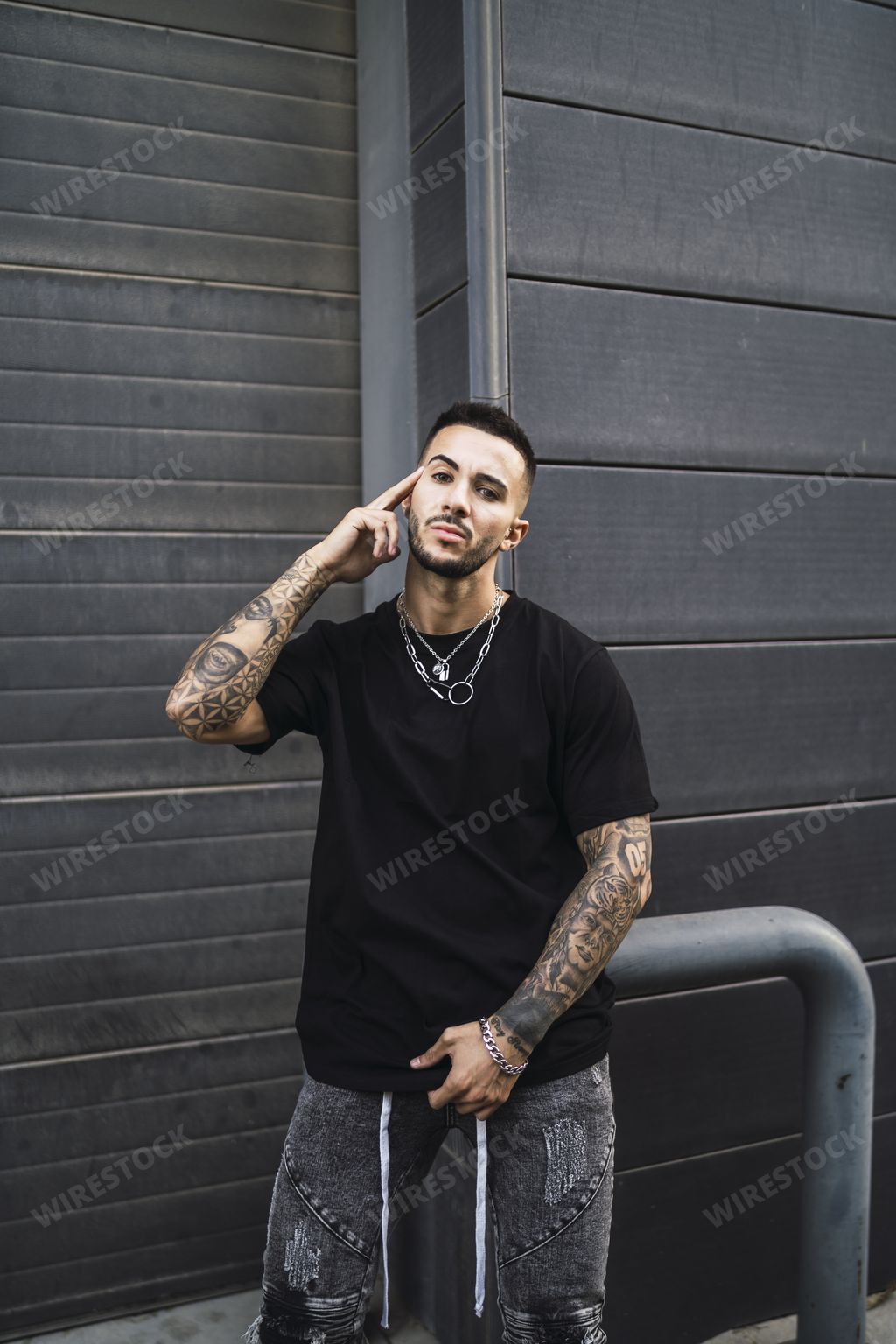 A portrait of a hot young stylish man wearing a black T-shirt and gray jeans