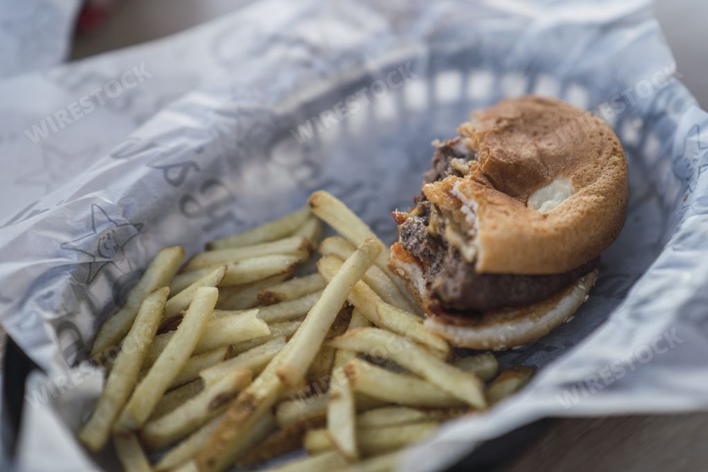 A closeup of a half eaten burger with fries in a fast food platter