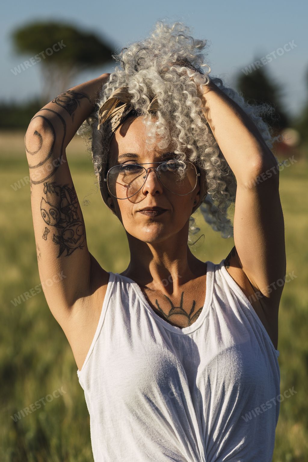 A curly-haired Spanish cute woman with tattoos in a wheat field