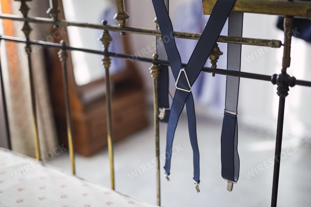 Dark blue suspenders hanging on old metal headboard