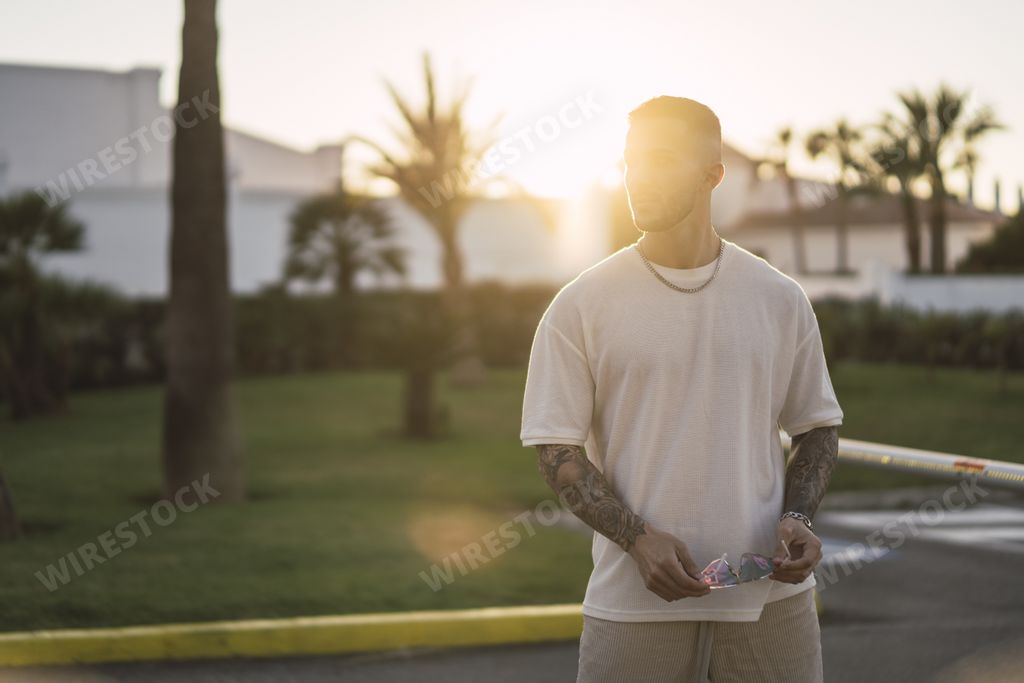 A shallow focus shot of a handsome Spanish Caucasian man with tattoos and sunglasses posing outdoors