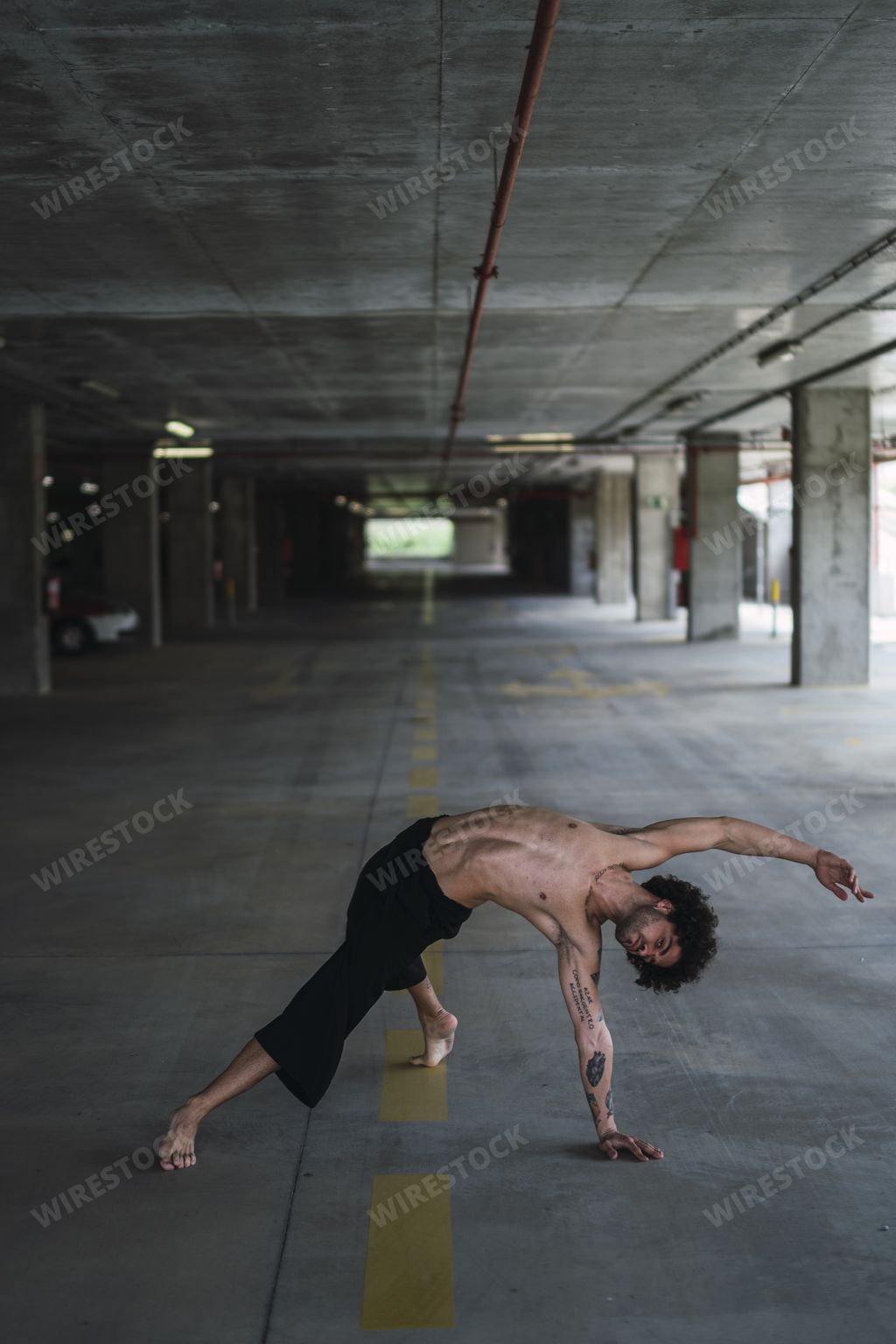 A vertical shot of a half-naked athletic European guy with tattoos exercising