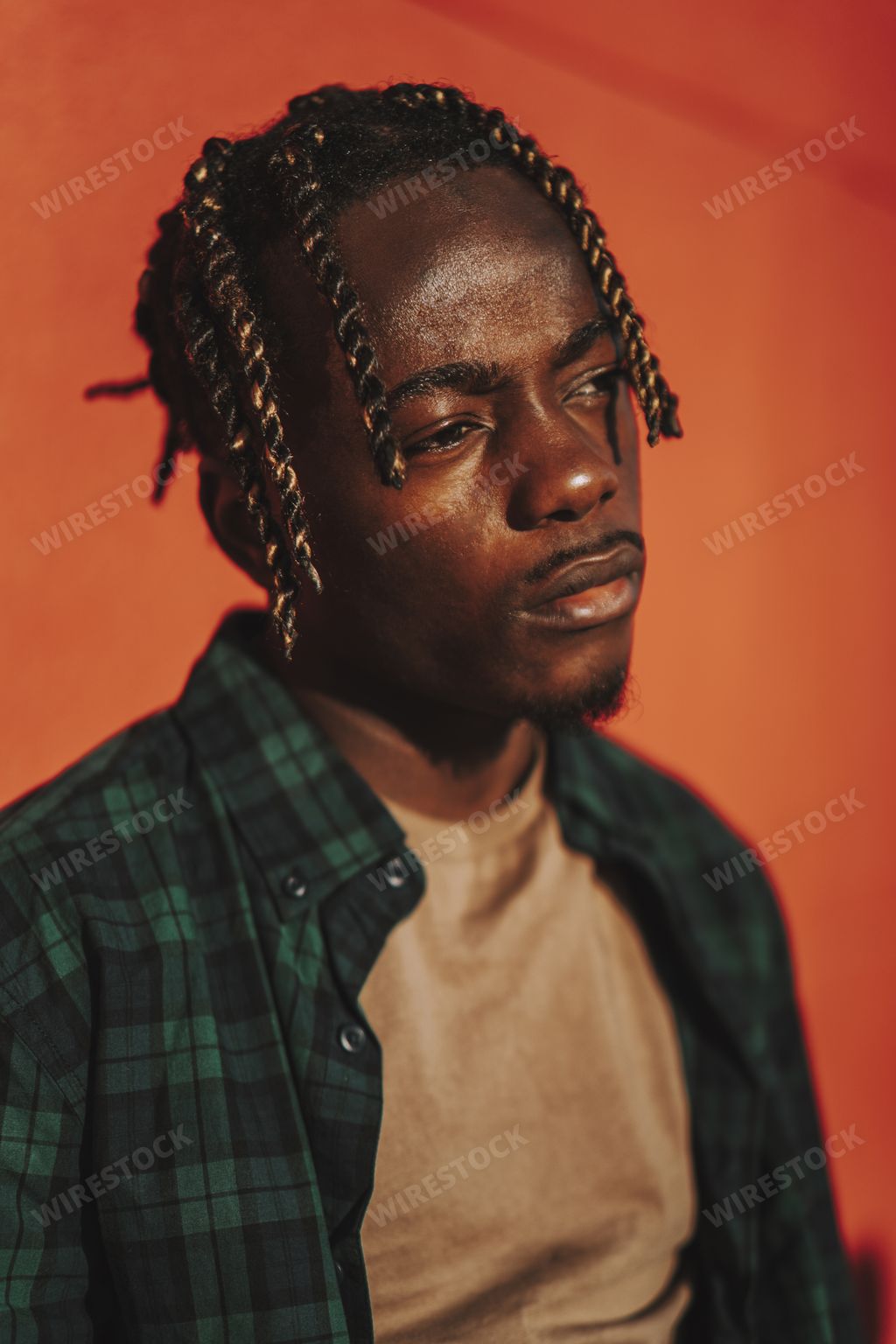 A handsome stylish Spanish man with dreads posing with a serious facial expression