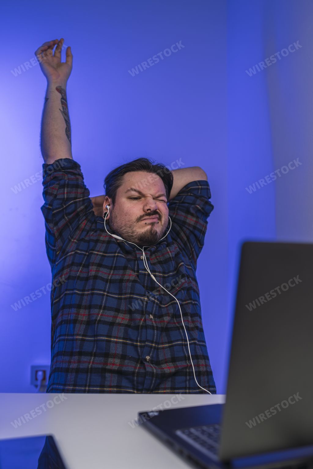 A tired man leaning on his chair and stretching while working