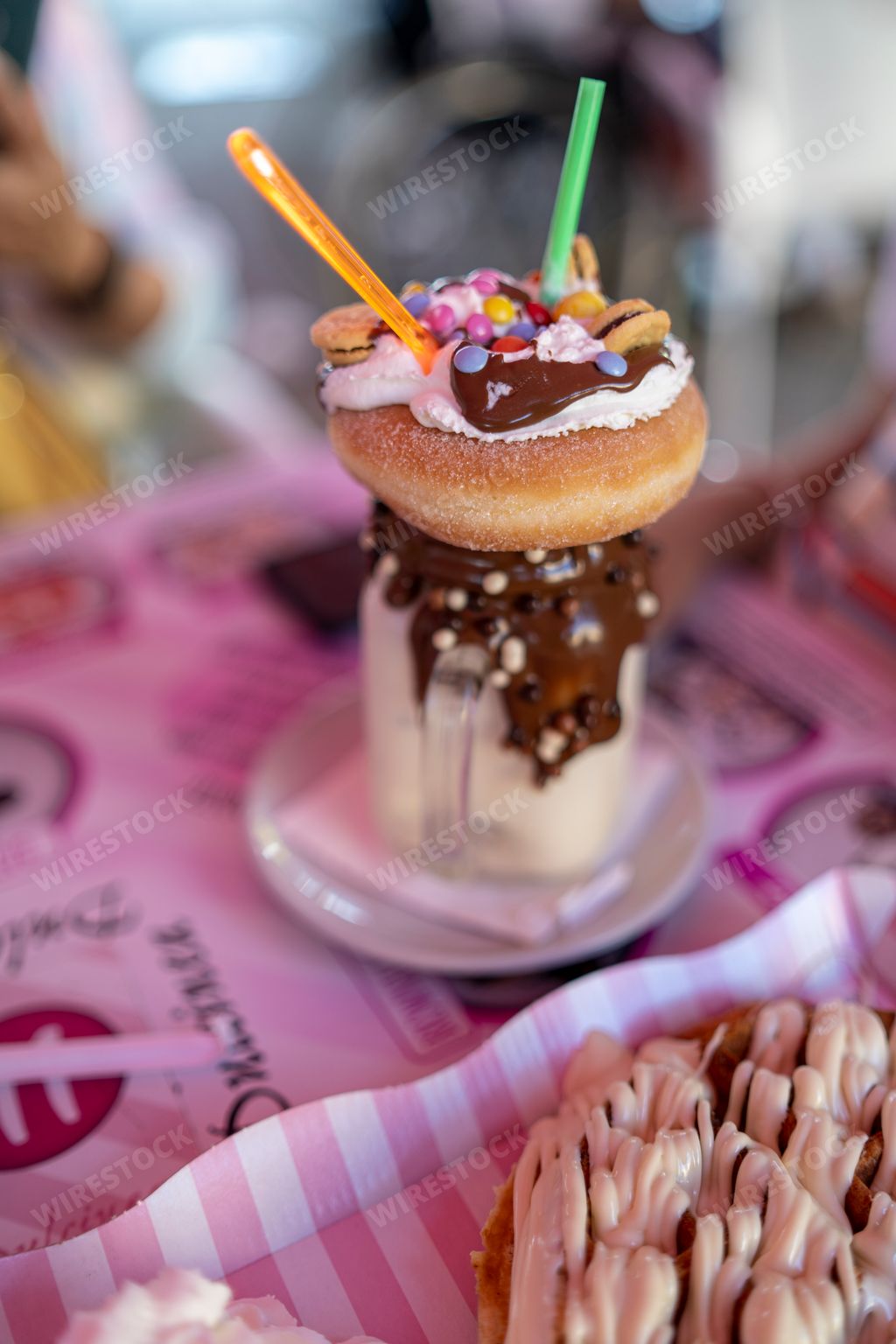 A vertical closeup of a chocolate milkshake with a donut.