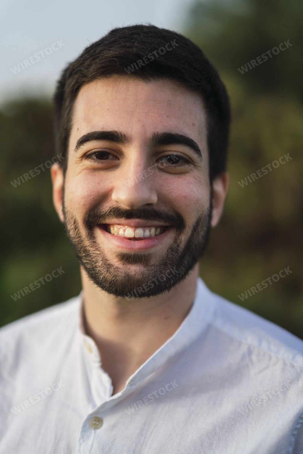 A vertical shot of the happy portrait of a Spanish Caucasian young man in the park