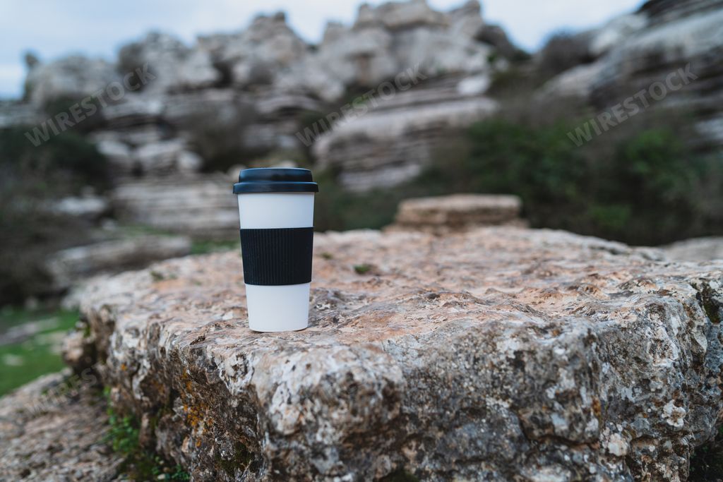 A close-up shot of a cup of coffee on a rock during daytime with blurred background in El Torcal de Antequera, Malaga, Spain