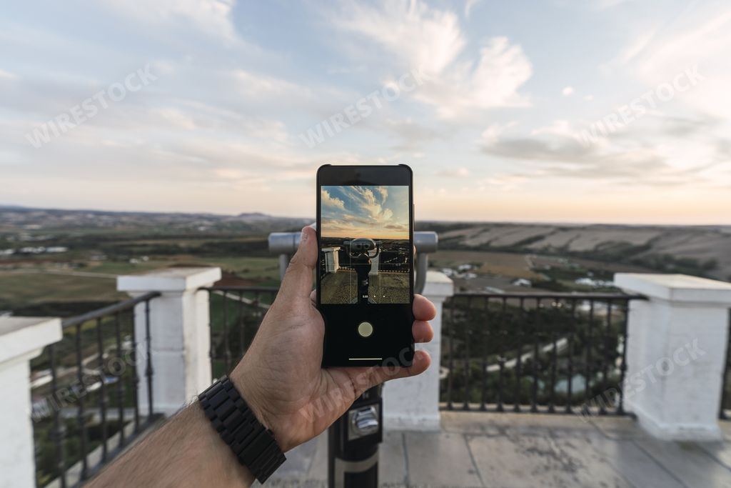 A closeup of a person taking a picture of hills in Arcos de la Frontera with a phone in Cadiz, Spain