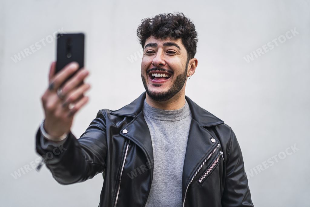 A handsome European male in a black leather jacket making a video call from his mobile phone