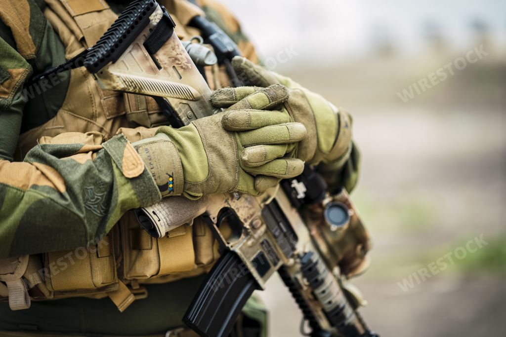 A shallow focus of a special force soldier holding his gun outdoors with a blurry background