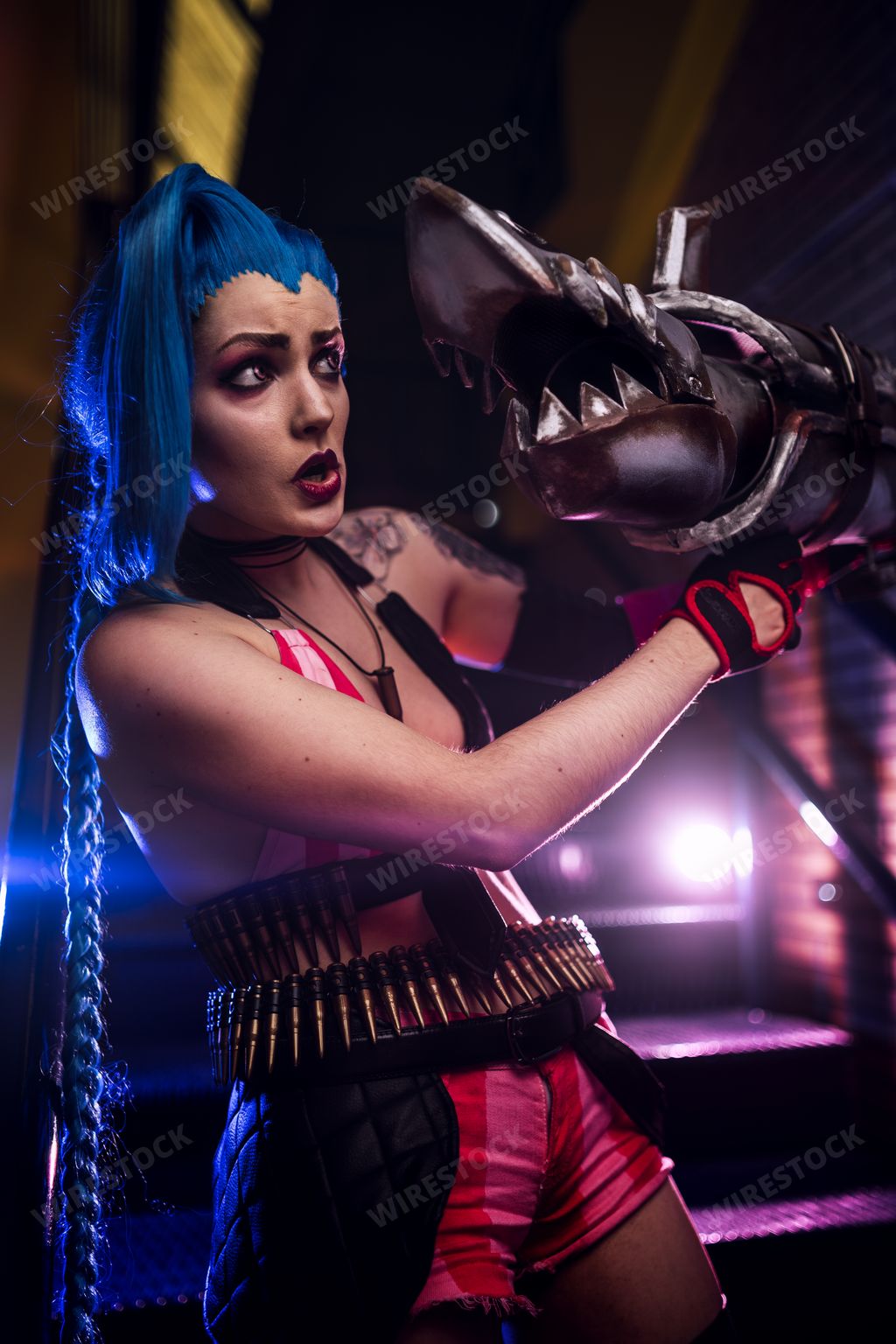 A vertical shot of a young female with tattoos standing on the stairs with a shark figure