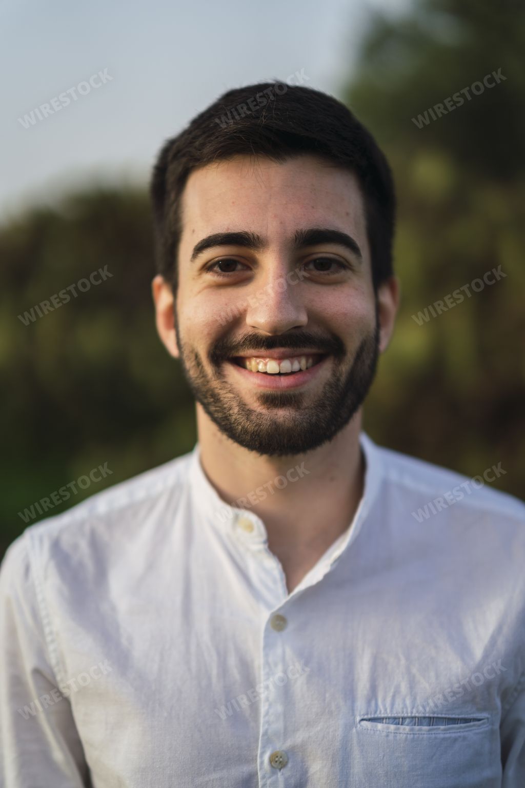 A vertical shot of the happy portrait of a Spanish Caucasian young man in the park