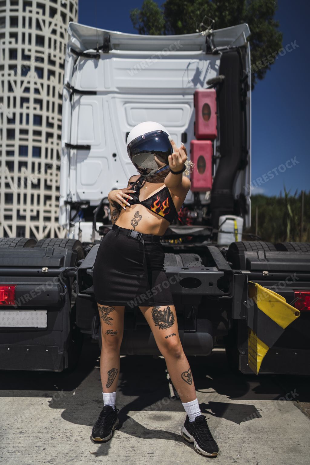 A confident female with tattoos wearing a helmet and showing a middle finger under the sunlight in Spain