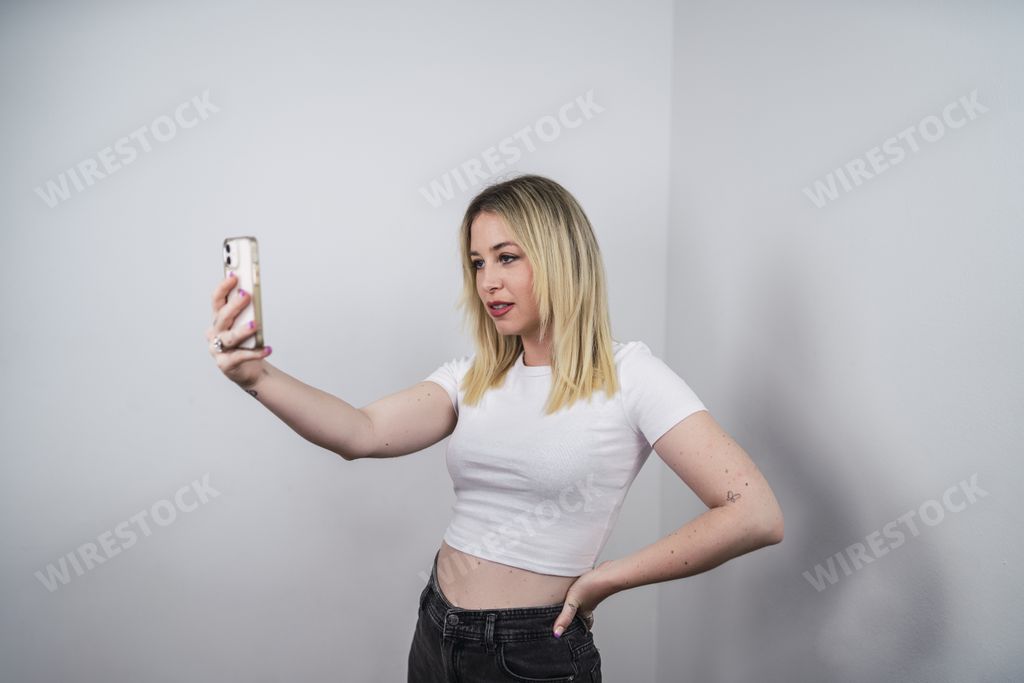 A stylish Spanish female taking a selfie on white background