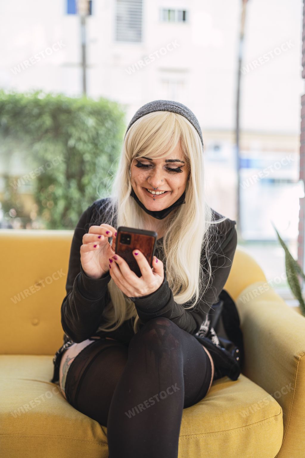 A young Spanish woman with blond hair and a mask under her chin checking the phone