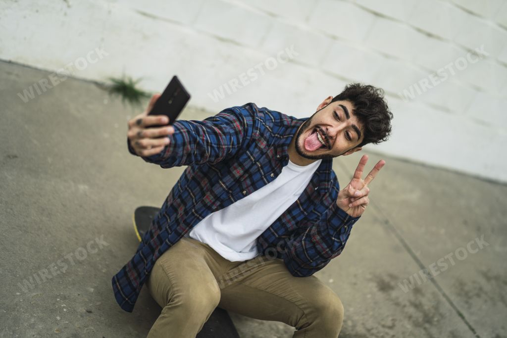 A cool Spanish male taking a selfie and showing the V sign