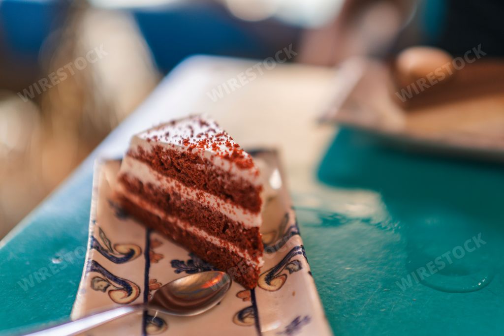 A closeup shot of a red velvet cake slice and a spoon on a tray on an isolated background