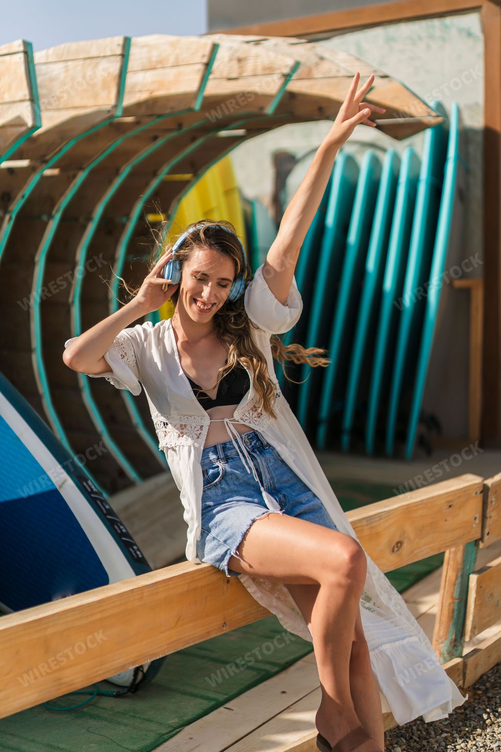 A vertical shot of a young, beautiful Spanish woman with headphones posing by the beach