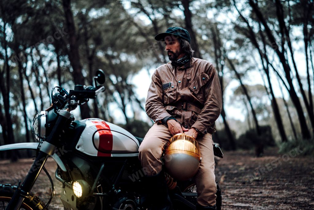 Man with helmet sits on motorcycle in forest