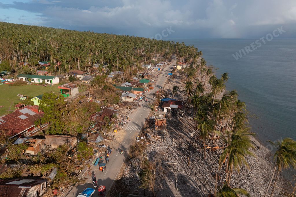 A bird's eye view of country houses by a road surrounded by tropical trees
