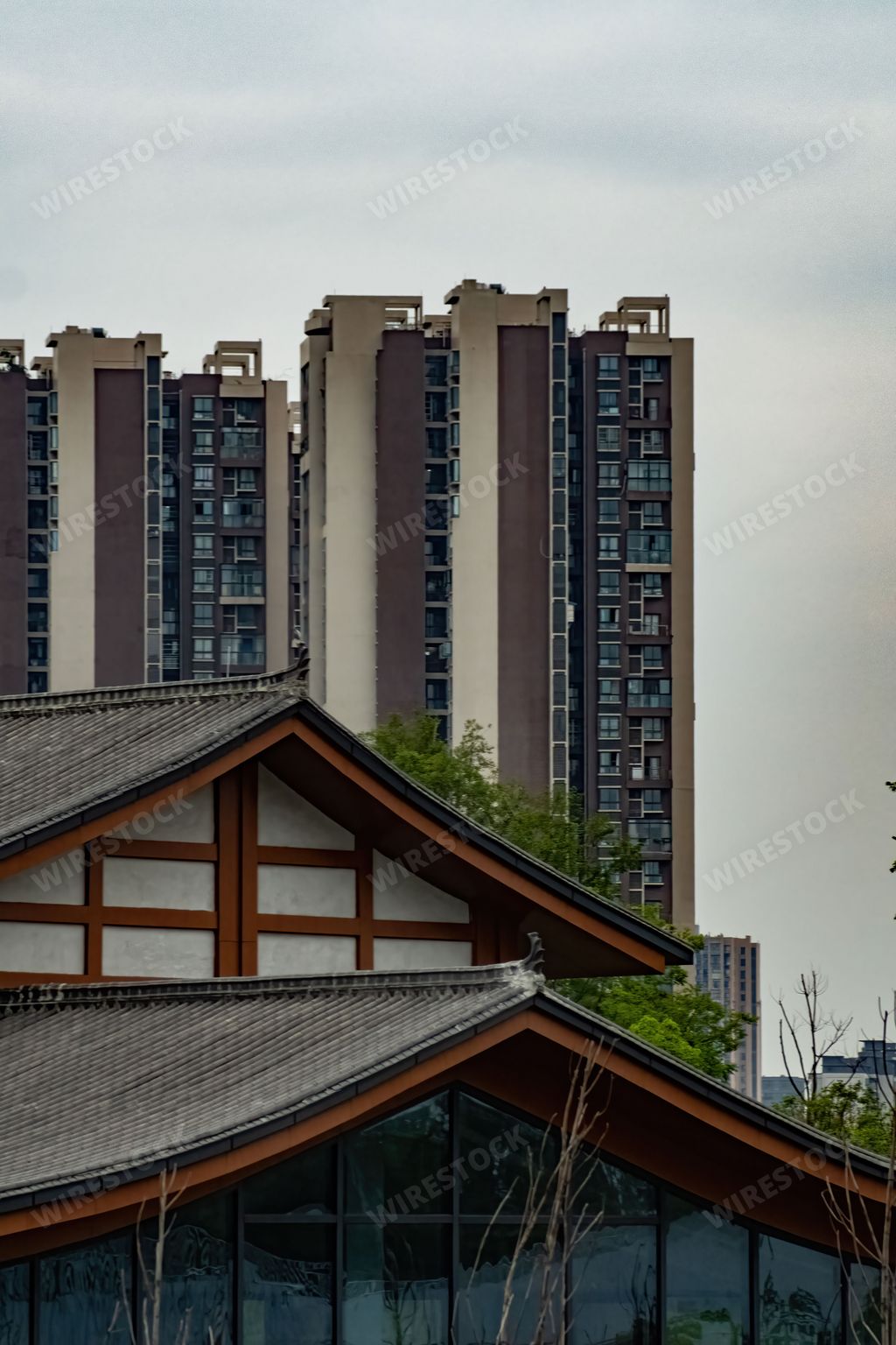 A vertical shot of a Asian style modern house on residential skyscrapers background in Sichuan Province, China