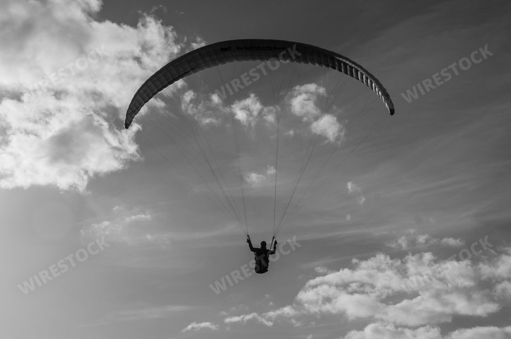 A beautiful grayscale of a paraglider silhouette flying in the sky