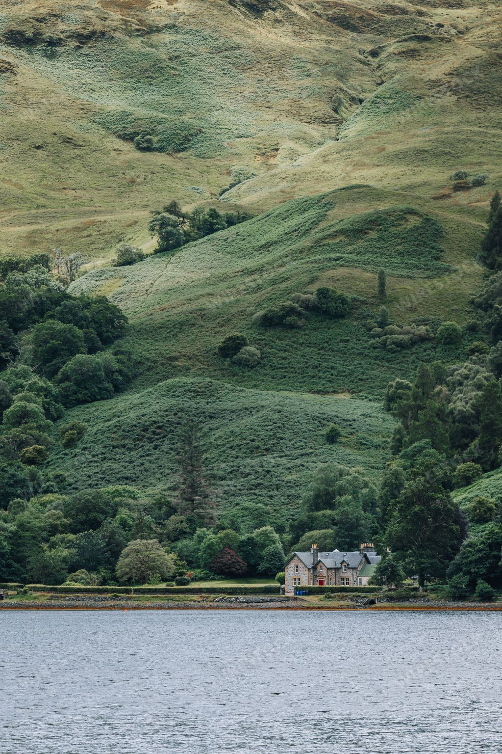 A vertical distant view of a house at the coast of a water in Skye island, Scotland, UK
