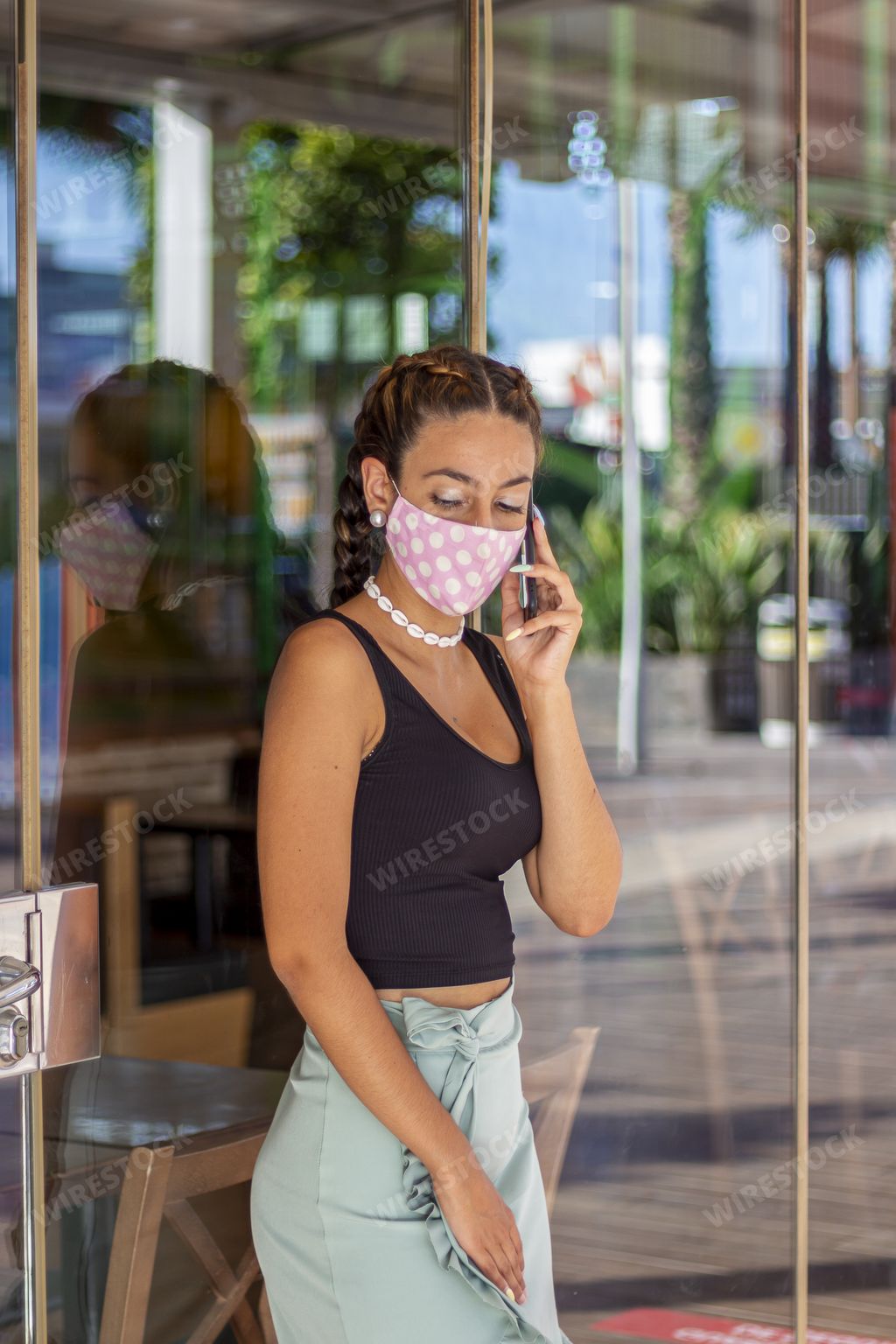 A young female in a medical mask talking on phone - the concept of new normal