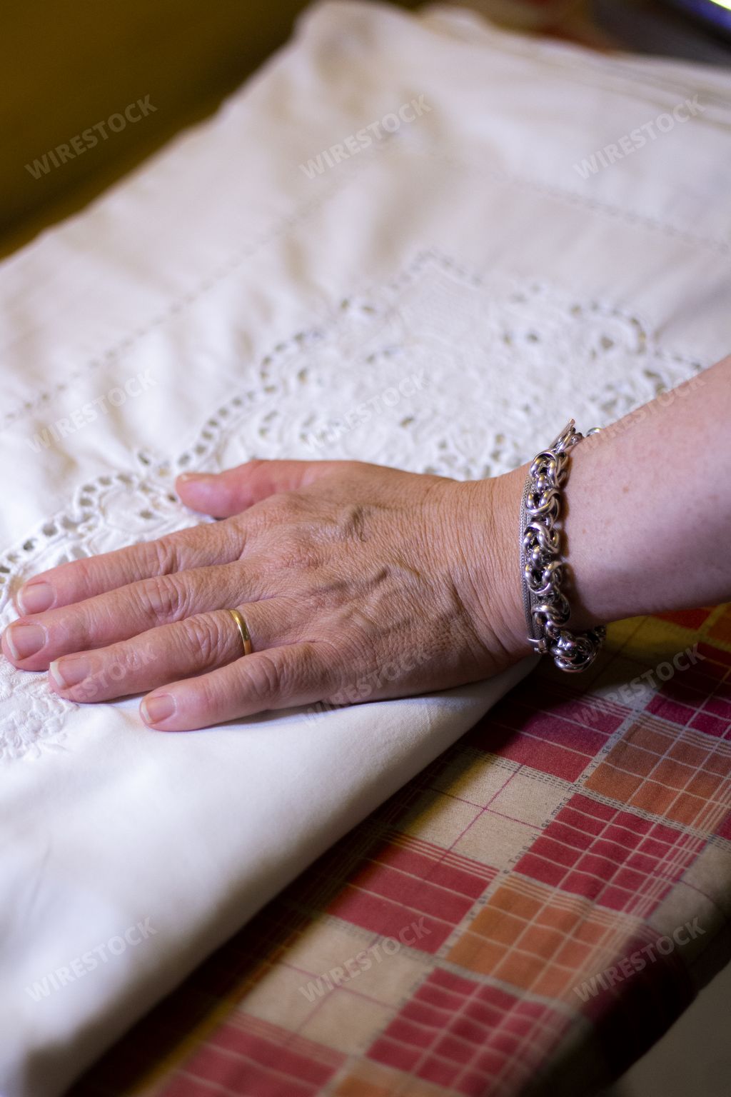 A vertical shot of a woman hand put on a white fabric with patterns