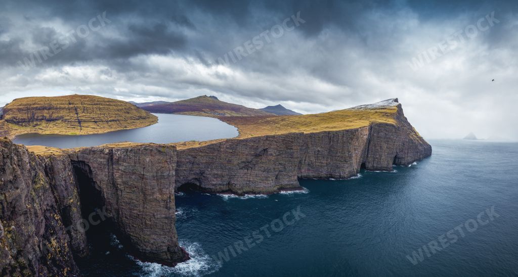 A landscape of Sorvagsvatn lake in the Faroe Islands by tranquil water  under gray cloudy sky