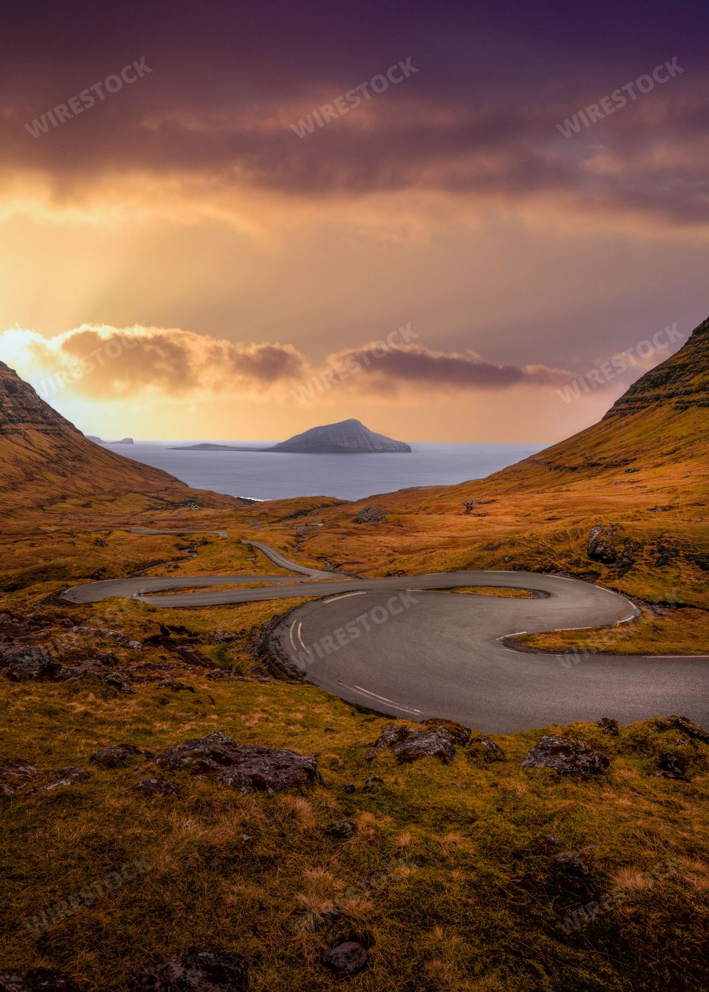 A landscape view of Nororadalur island green hills by water under at sunset in Streymoy, Faroe Islands