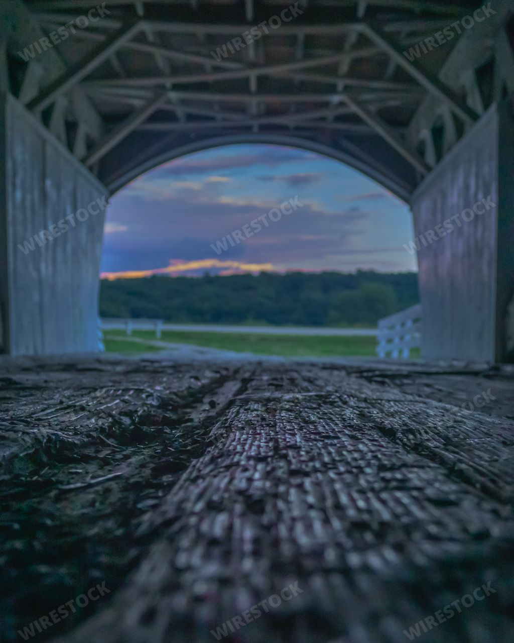 A closeup shot of a wooden bridge structure with amazing greenery in the background