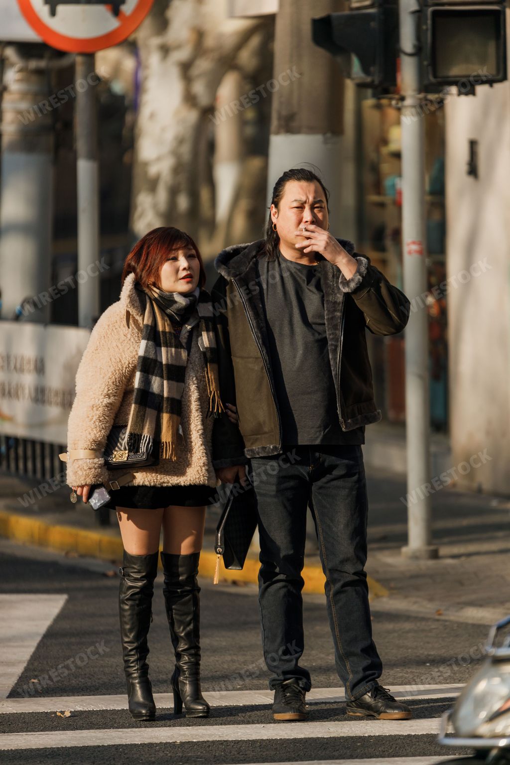 A vertical shot of a chinese young couple down the street with a building on the background
